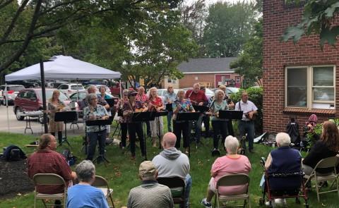 Members of a ukulele band play for seniors outside 