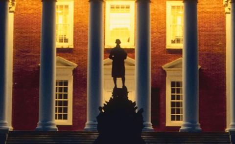 Photo of a statue silhouetted against a college building
