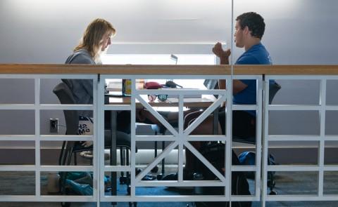 Two students talk while sitting in the Portland Campus library