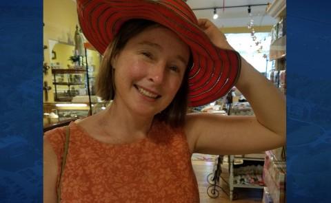 Susan McHugh poses wearing a red hat